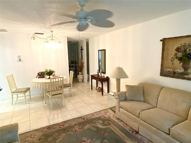 tiled living room with ceiling fan with notable chandelier and a textured ceiling