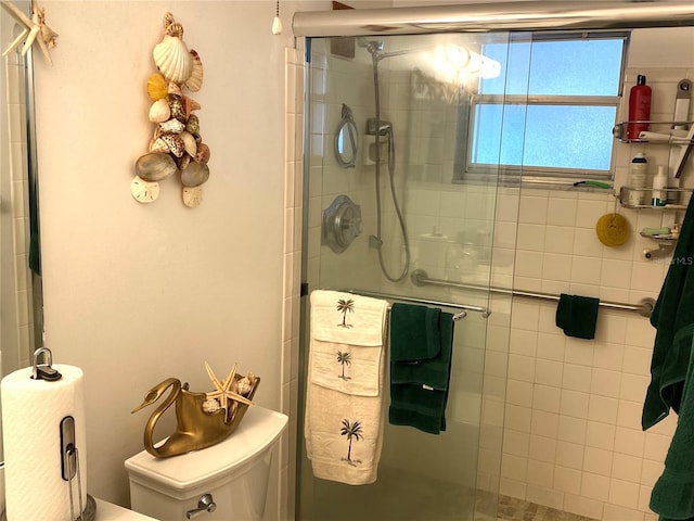 bathroom featuring toilet and a shower with shower door