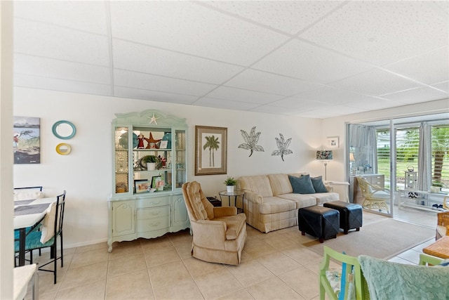 living room with a paneled ceiling and light tile patterned floors