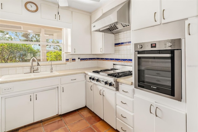 kitchen featuring tile patterned flooring, tasteful backsplash, wall chimney range hood, white cabinetry, and appliances with stainless steel finishes