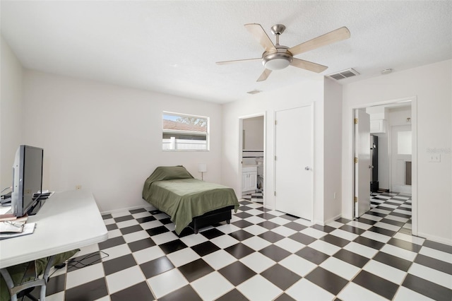 bedroom featuring ensuite bathroom, ceiling fan, and a textured ceiling