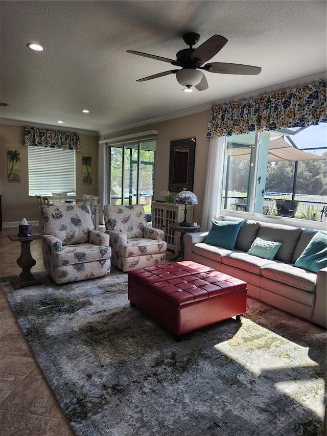 living room with ceiling fan, a textured ceiling, dark tile patterned floors, and ornamental molding