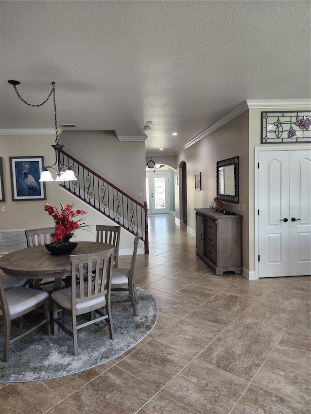 tiled dining space with a chandelier, a textured ceiling, and ornamental molding