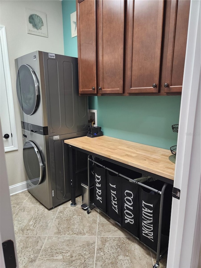 laundry area featuring cabinets and stacked washer and clothes dryer