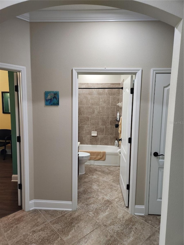 bathroom with toilet, tiled shower / bath combo, tile patterned flooring, and crown molding