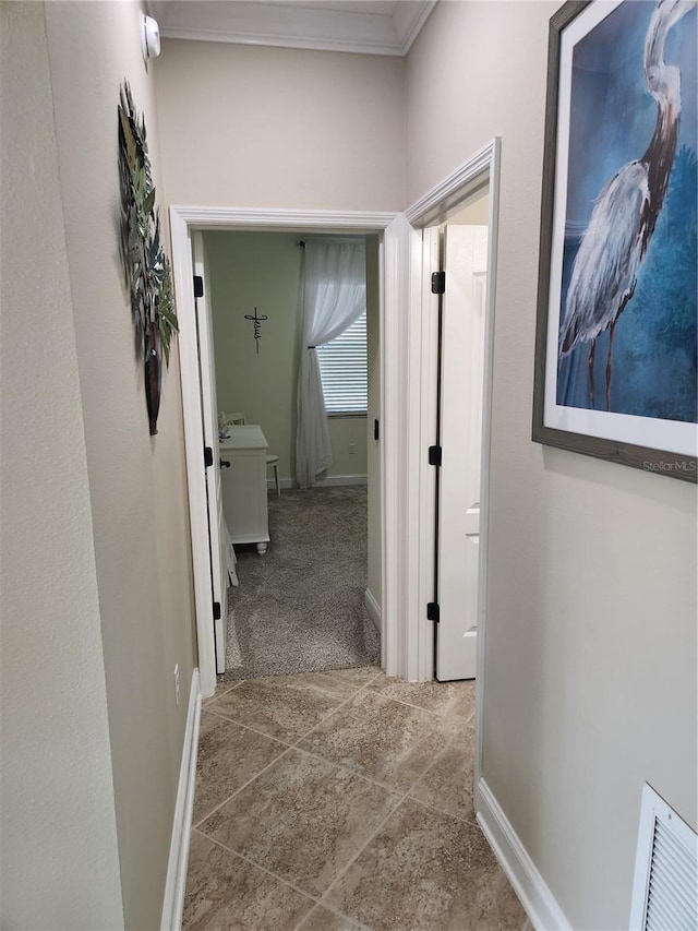 hall featuring light tile patterned floors and crown molding