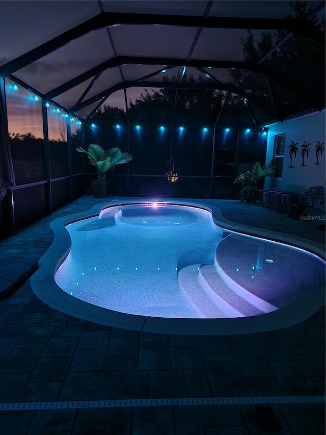 pool at dusk featuring a jacuzzi and a lanai