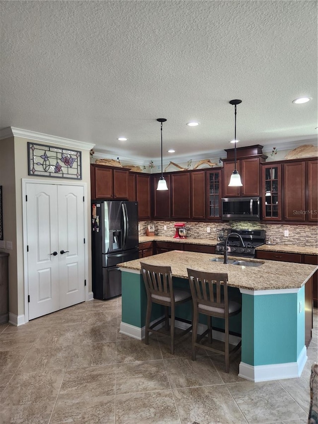 kitchen with stainless steel appliances, a center island with sink, sink, a textured ceiling, and pendant lighting