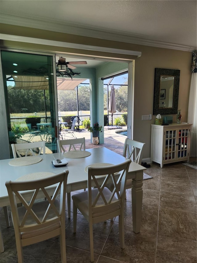 tiled dining area featuring ceiling fan and crown molding