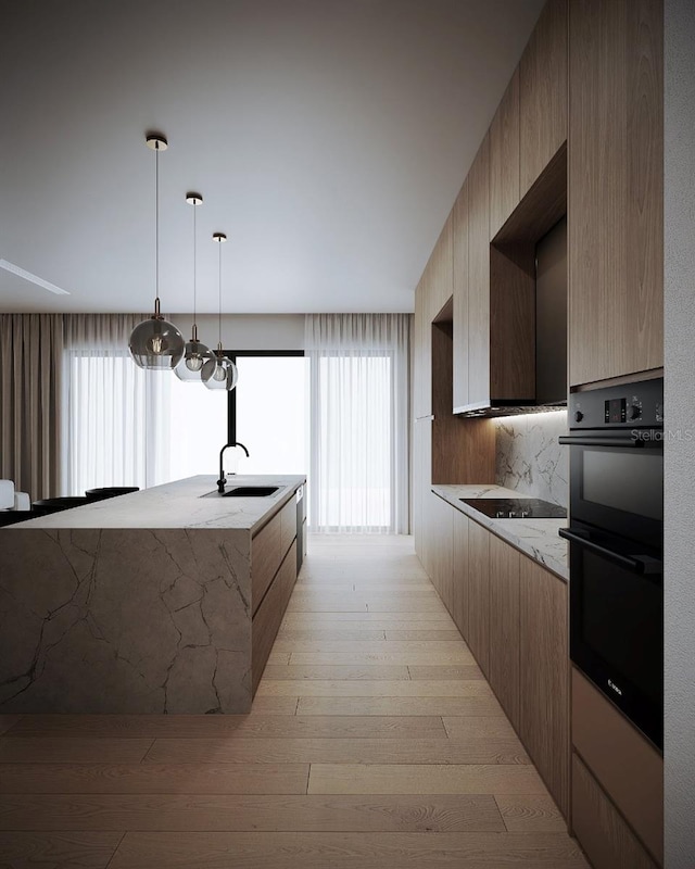 kitchen with sink, black appliances, light stone countertops, light hardwood / wood-style flooring, and pendant lighting