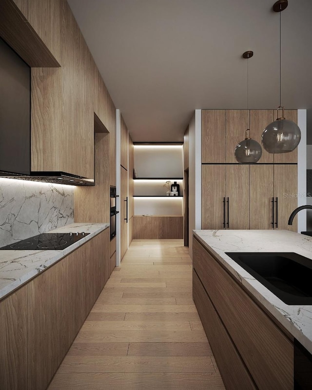 kitchen featuring black electric cooktop, sink, light stone countertops, pendant lighting, and light wood-type flooring