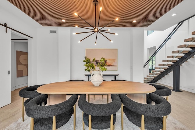 2038 Datura St, Sarasota, FL 34239 - dining area with a barn door, visible vents, stairs, a chandelier, and light wood-type flooring