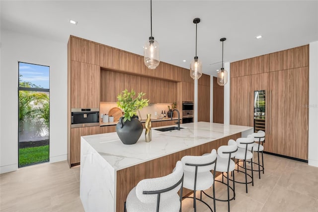 2038 Datura St, Sarasota, FL 34239 - kitchen featuring a breakfast bar area, light stone counters, modern cabinets, a sink, and a large island with sink