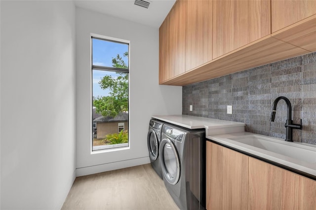 2038 Datura St, Sarasota, FL 34239 - washroom featuring washing machine and dryer, visible vents, a sink, light wood-style floors, and cabinet space