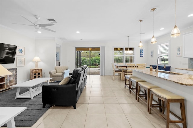 tiled living room with ceiling fan, sink, and ornamental molding