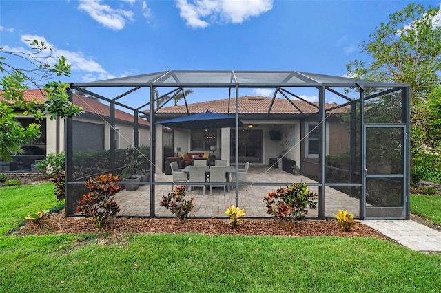 back of property featuring a lawn, glass enclosure, and a patio area