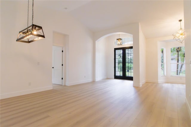 spare room featuring high vaulted ceiling, french doors, a notable chandelier, and light hardwood / wood-style flooring