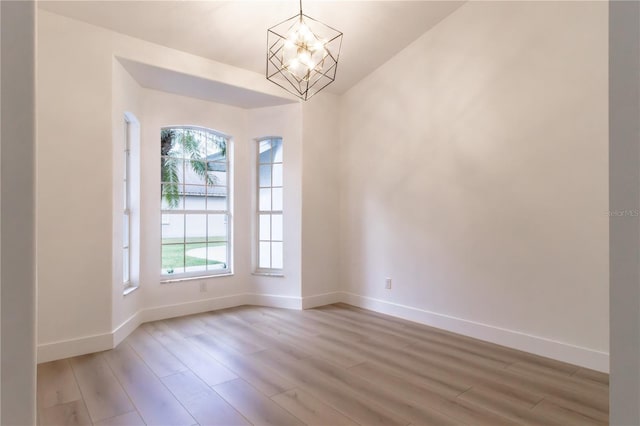 unfurnished room featuring light hardwood / wood-style floors and a chandelier