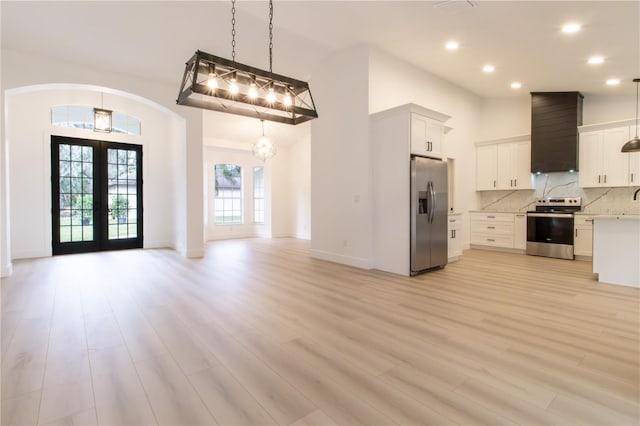 kitchen featuring french doors, light hardwood / wood-style floors, white cabinets, appliances with stainless steel finishes, and decorative light fixtures