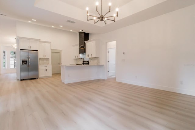 kitchen featuring stainless steel refrigerator with ice dispenser, kitchen peninsula, decorative backsplash, white cabinetry, and light hardwood / wood-style flooring