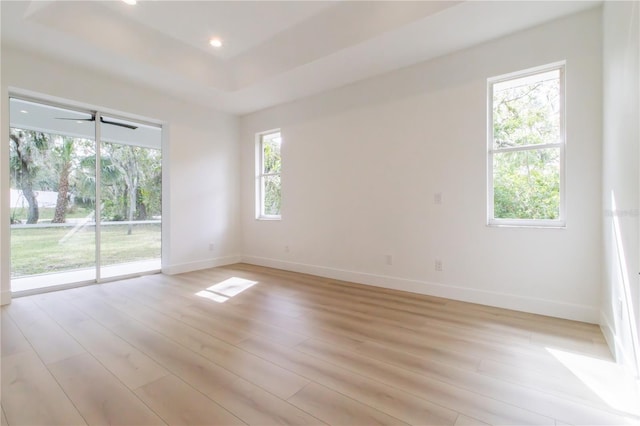 spare room featuring light wood-type flooring, ceiling fan, and plenty of natural light