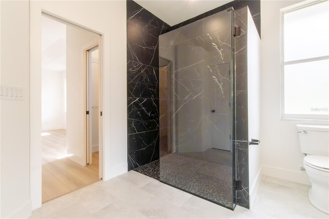 bathroom featuring tile patterned flooring, toilet, and a tile shower