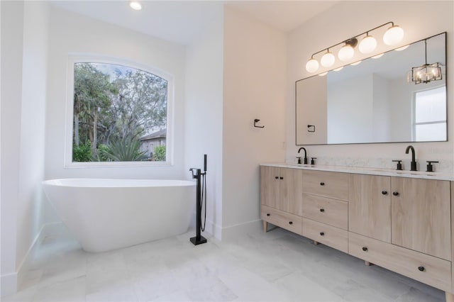 bathroom featuring a tub to relax in, vanity, and an inviting chandelier