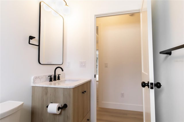 bathroom with toilet, vanity, and hardwood / wood-style flooring