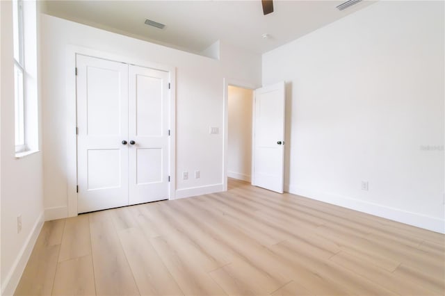 unfurnished bedroom featuring light hardwood / wood-style floors, ceiling fan, and a closet