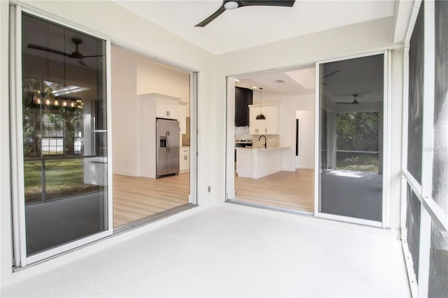 unfurnished sunroom with ceiling fan