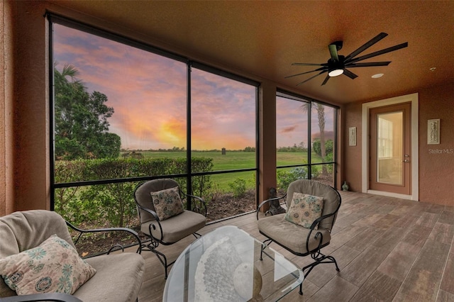 sunroom with ceiling fan and a rural view