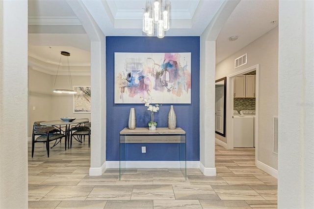 hall with separate washer and dryer, a notable chandelier, crown molding, and a tray ceiling