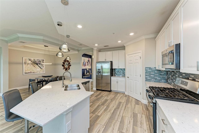 kitchen featuring stainless steel appliances, sink, hanging light fixtures, a kitchen island with sink, and crown molding