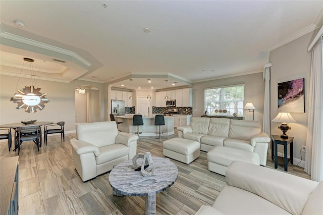 living room with a raised ceiling, light hardwood / wood-style floors, and crown molding