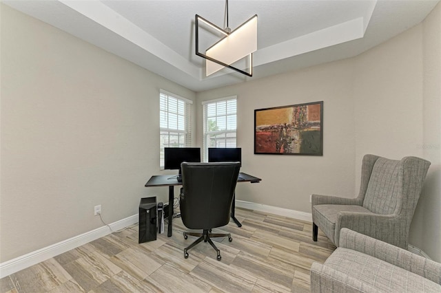 office space featuring light wood-type flooring and a tray ceiling