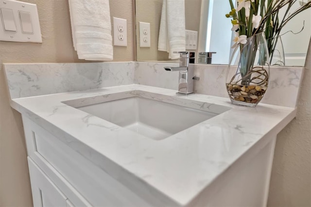 kitchen featuring light stone counters, sink, and white cabinets