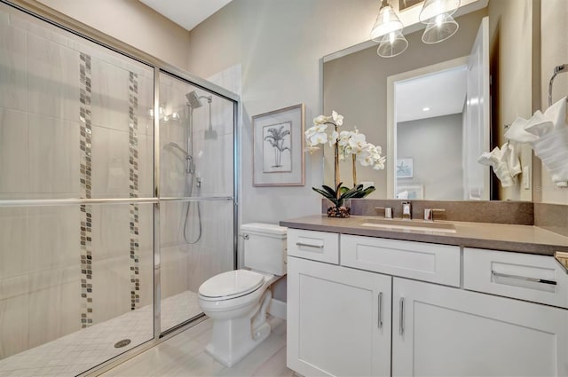 bathroom with a shower with door, vanity, and toilet