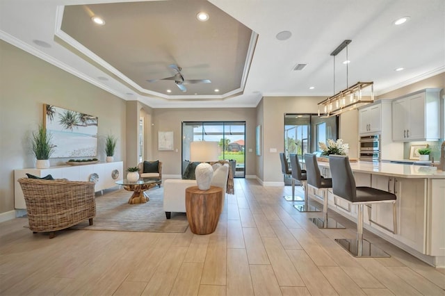 living room with a raised ceiling, light hardwood / wood-style flooring, and crown molding