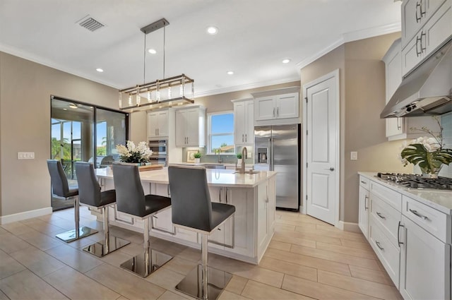 kitchen with white cabinets, decorative light fixtures, stainless steel appliances, and a wealth of natural light