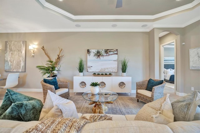 living room with a tray ceiling and ornamental molding