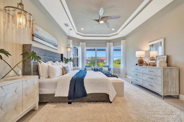 bedroom featuring a raised ceiling, crown molding, and ceiling fan with notable chandelier