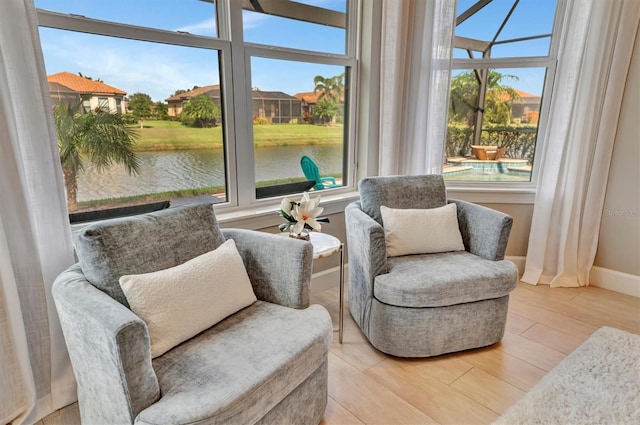 living area with a water view, a wealth of natural light, and light hardwood / wood-style flooring