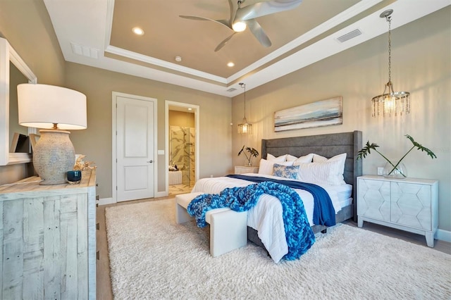 bedroom featuring a tray ceiling, ensuite bath, ceiling fan, and hardwood / wood-style flooring