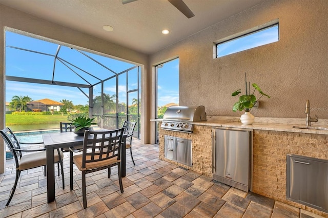 view of patio / terrace with glass enclosure, sink, exterior kitchen, grilling area, and a water view