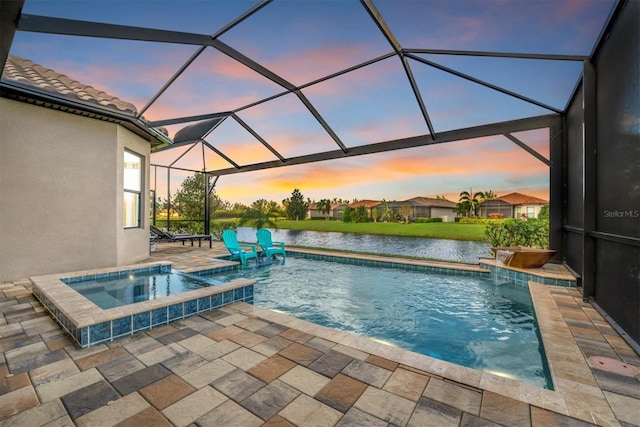 pool at dusk with glass enclosure, pool water feature, a patio area, an in ground hot tub, and a water view