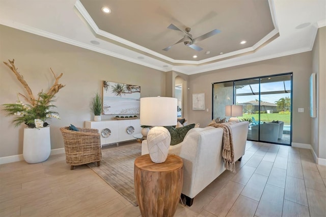 living room with a tray ceiling, light hardwood / wood-style flooring, ceiling fan, and crown molding