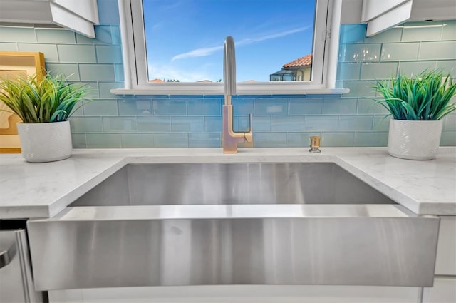 interior details with decorative backsplash, light stone counters, and sink