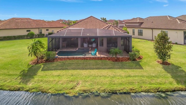 back of house featuring glass enclosure, a patio area, a yard, and a water view