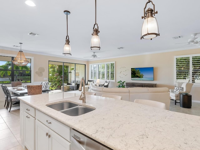 kitchen with white cabinetry, sink, light stone counters, hanging light fixtures, and crown molding