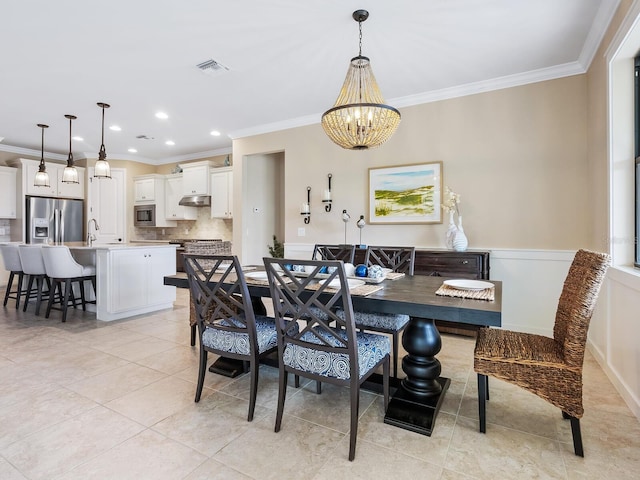 dining room with sink, light tile patterned floors, an inviting chandelier, and crown molding